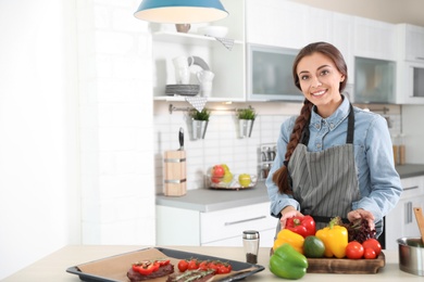 Professional female chef standing near table in kitchen