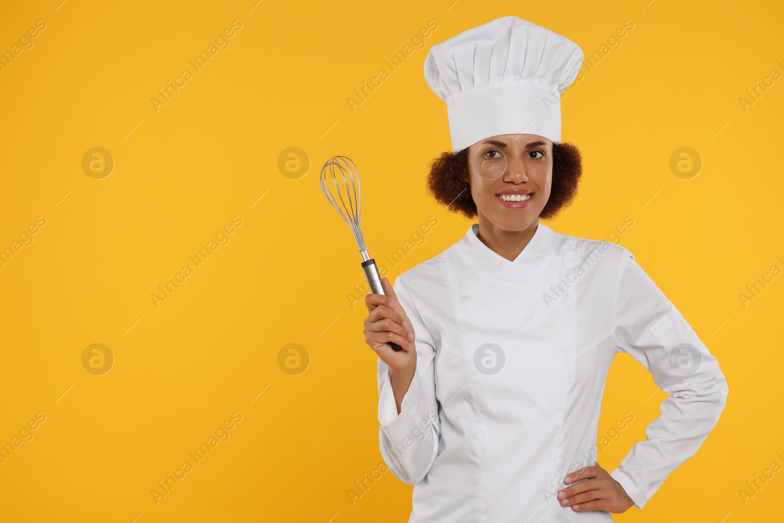 Photo of Happy female chef in uniform holding whisk on orange background. Space for text