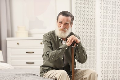 Senior man with walking cane on bed at home