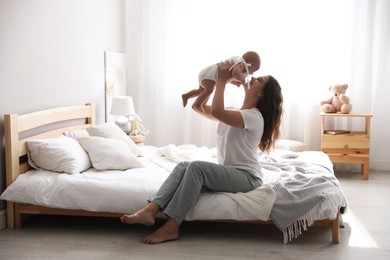 Photo of Happy young mother with her cute baby on bed at home