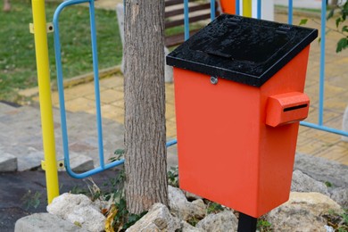 Photo of Red dog waste bin in park outdoors