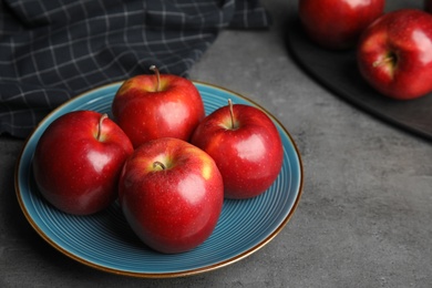 Photo of Plate with ripe juicy red apples on grey table