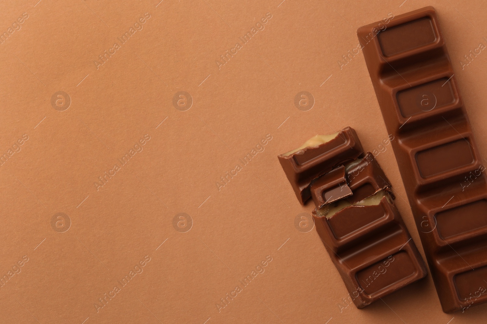 Photo of Delicious chocolate bars on light brown background, top view. Space for text