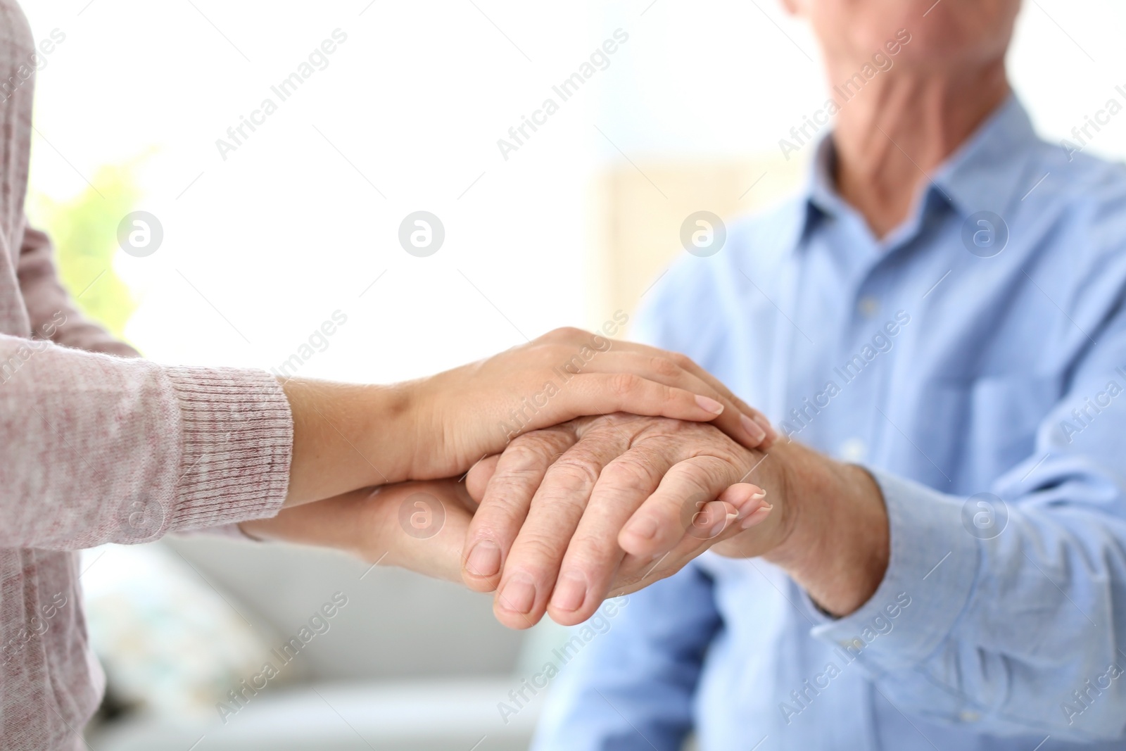 Photo of Helping hands on blurred background, closeup. Elderly care concept