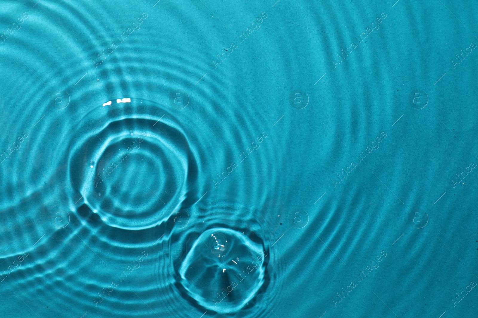 Photo of Rippled surface of clear water on light blue background, top view