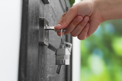 Photo of Woman unlocking door with key outdoors, closeup