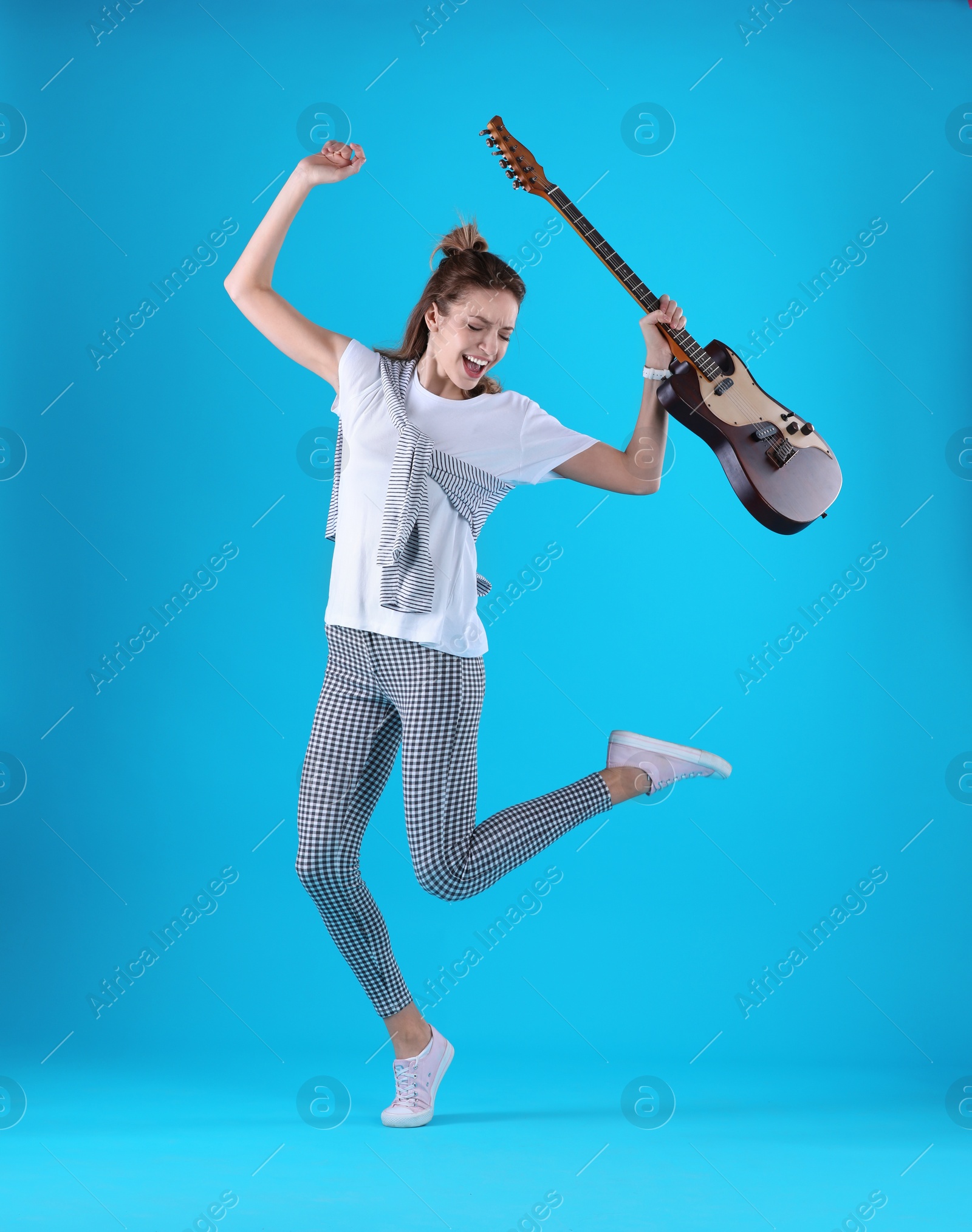 Photo of Young woman with electric guitar on color background