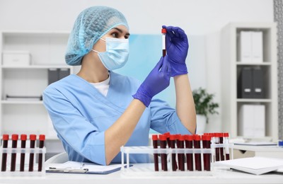 Laboratory testing. Doctor with blood samples in tubes at white table indoors