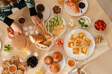 Photo of Woman serving food on table indoors, top view. Luxury brunch