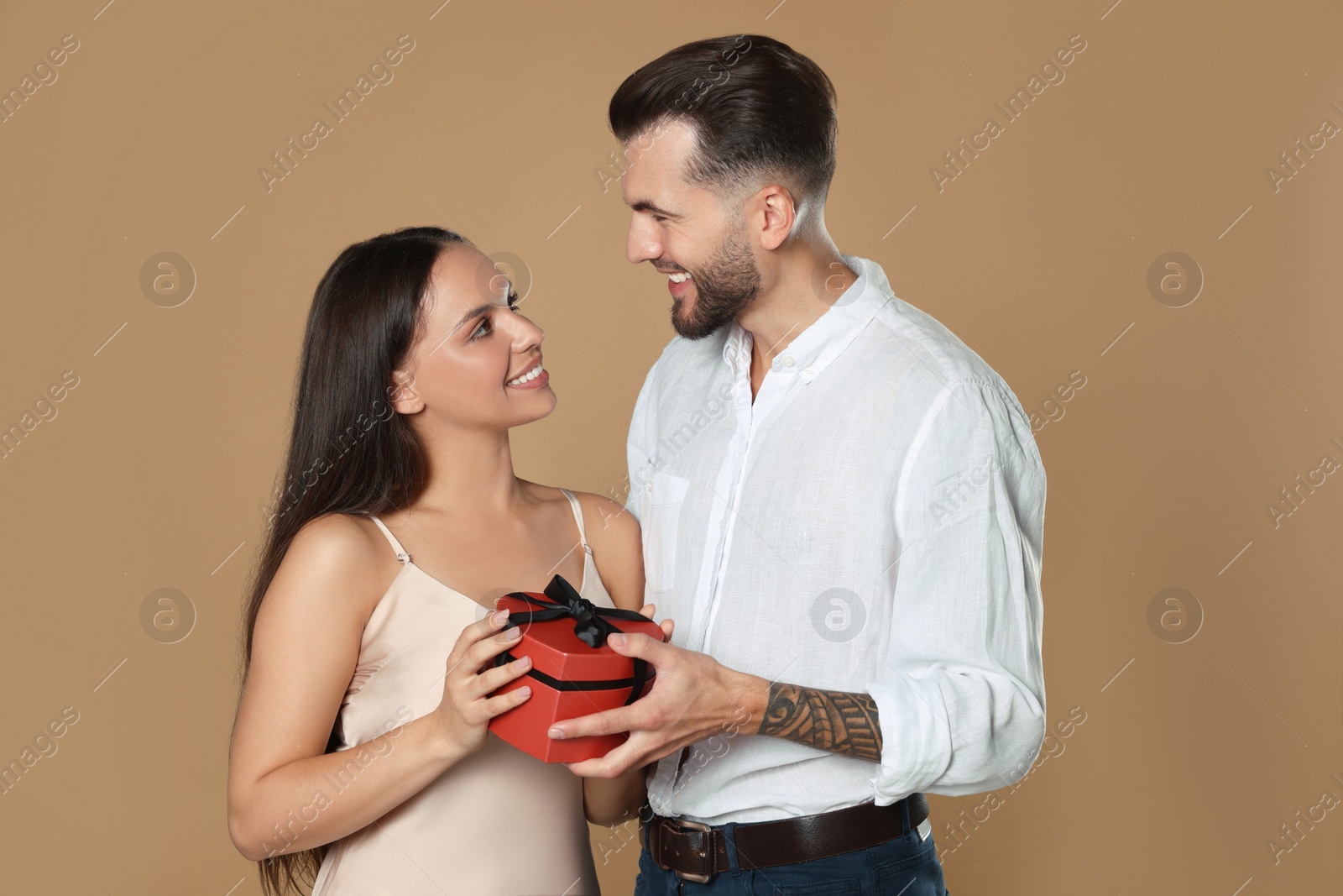 Photo of Lovely couple with gift on beige background