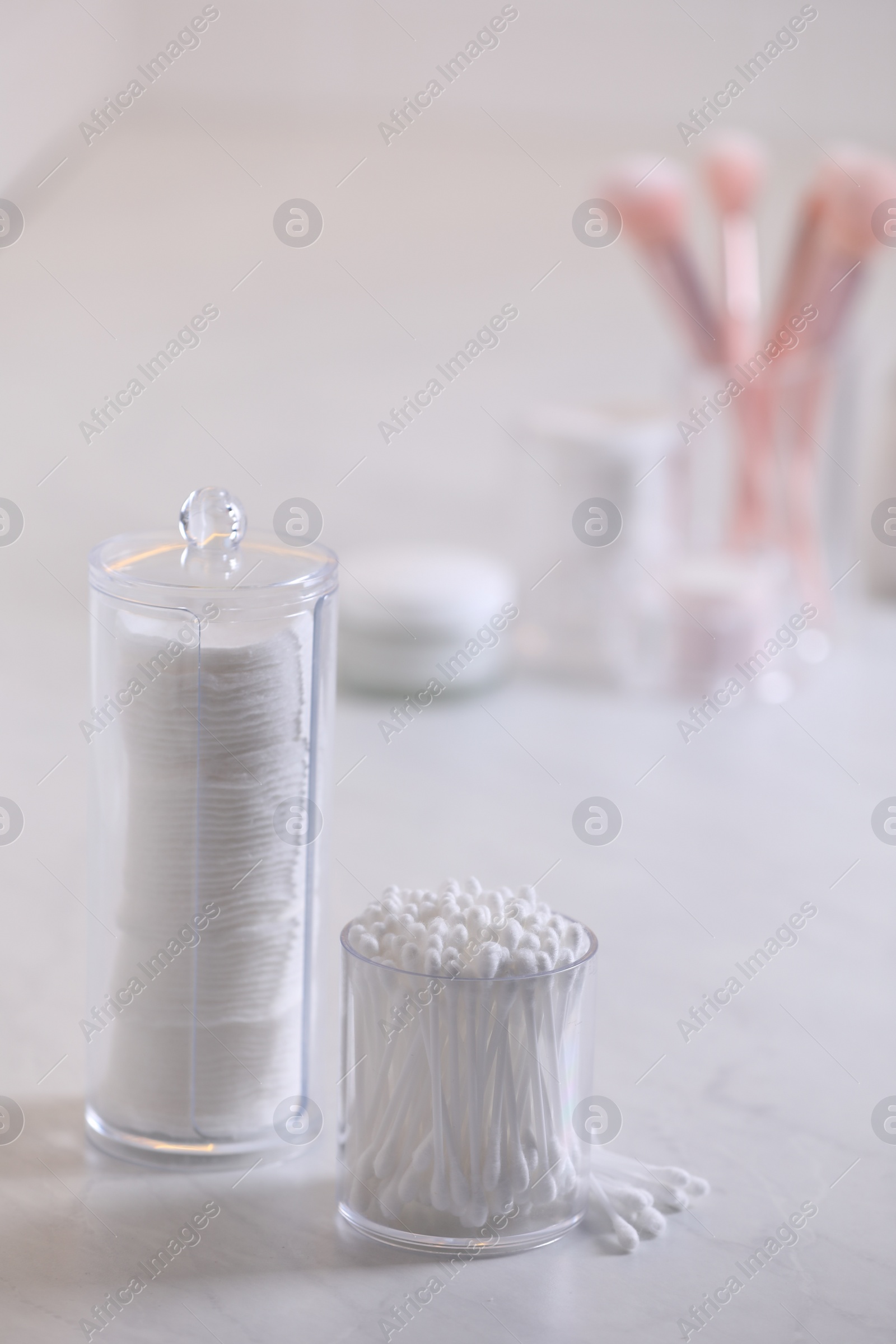 Photo of Cotton buds and pads in transparent holders on light table