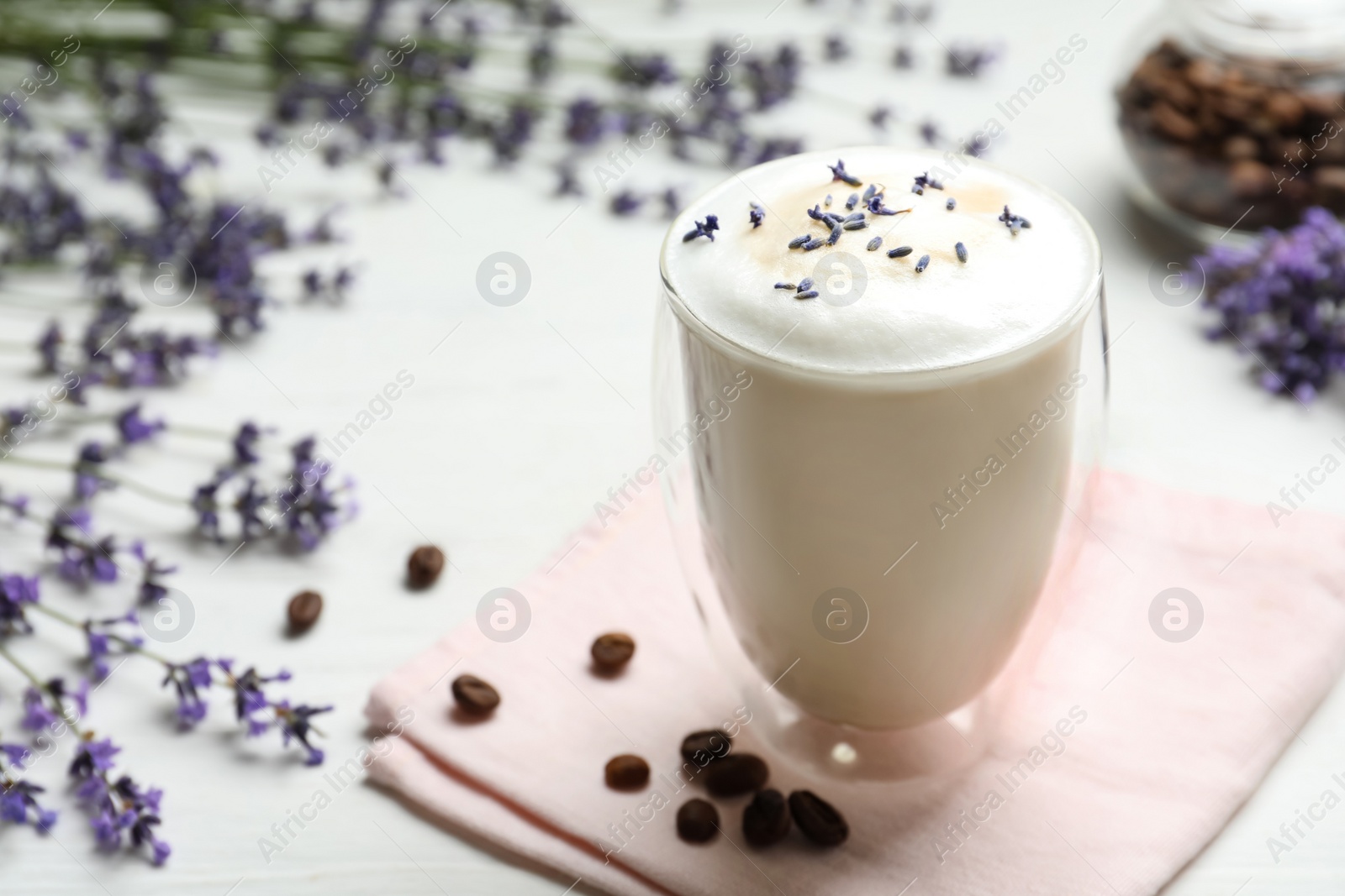 Photo of Delicious coffee with lavender and beans on white wooden table. Space for text