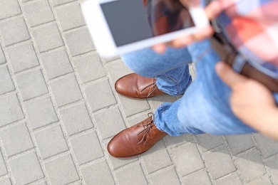 Photo of Man in stylish leather shoes using mobile phone outdoors, closeup