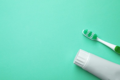 Photo of Blank tube of toothpaste and brush on color background, top view with space for text