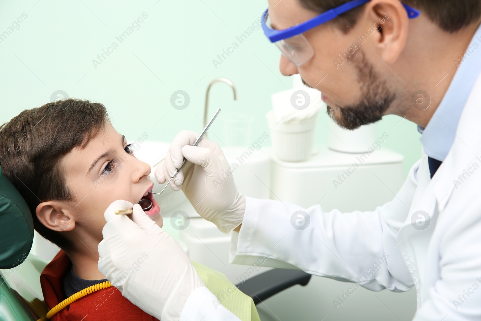 Photo of Professional dentist working with little patient in modern clinic