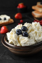 Tasty cream cheese and fresh berries on black table