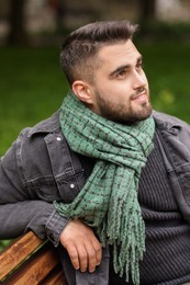 Smiling man in warm scarf on bench outdoors