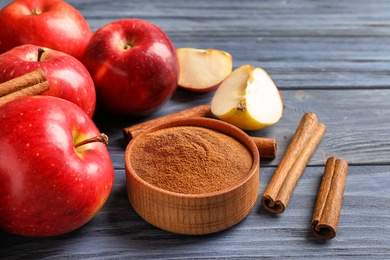 Photo of Fresh apples with cinnamon sticks and powder on wooden table, closeup