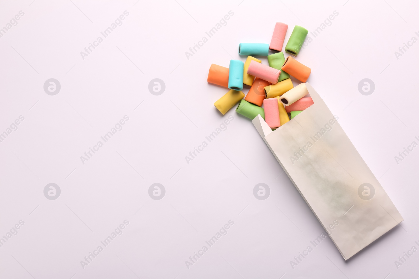 Photo of Paper bag with tasty liquorice candies on light background, top view. Space for text