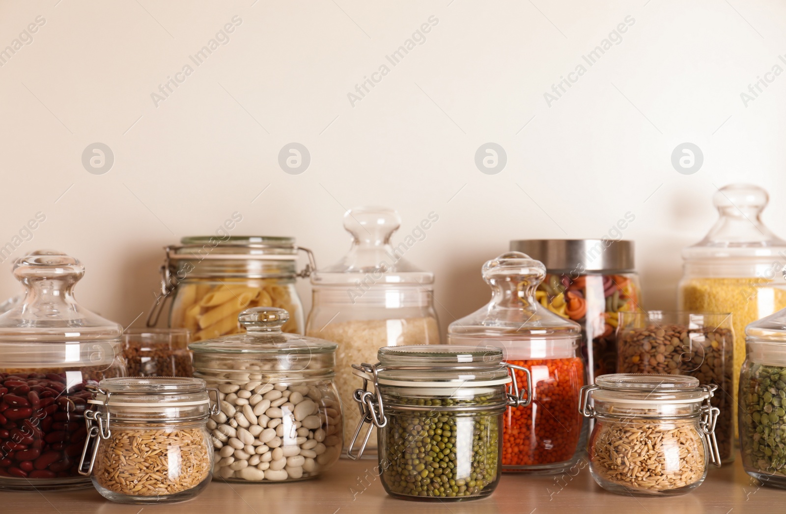 Photo of Glass jars with different types of groats on wooden shelf