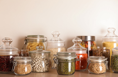 Glass jars with different types of groats on wooden shelf