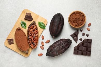 Flat lay composition with cocoa pods and chocolate on light table