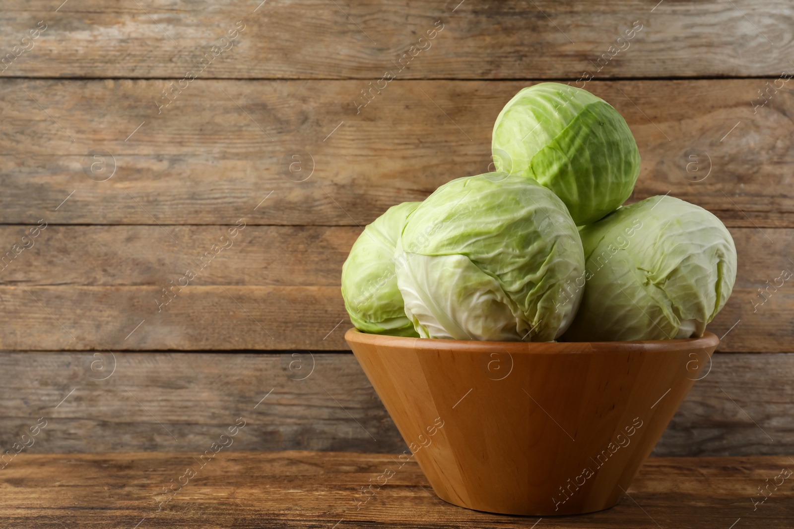 Photo of Ripe white cabbage on wooden table. Space for text