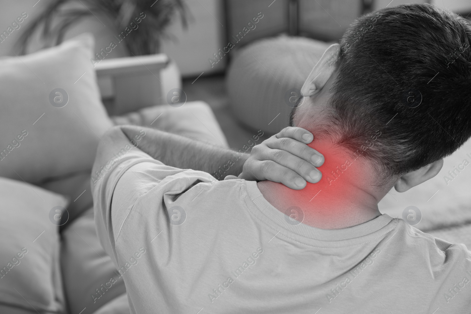 Image of Man suffering from neck pain at home, black and white effect