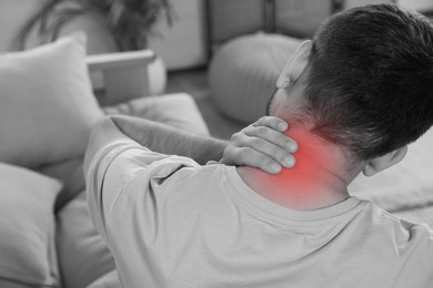 Image of Man suffering from neck pain at home, black and white effect