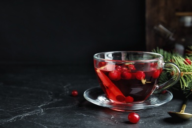 Photo of Tasty hot cranberry tea with lemon on black table. Space for text