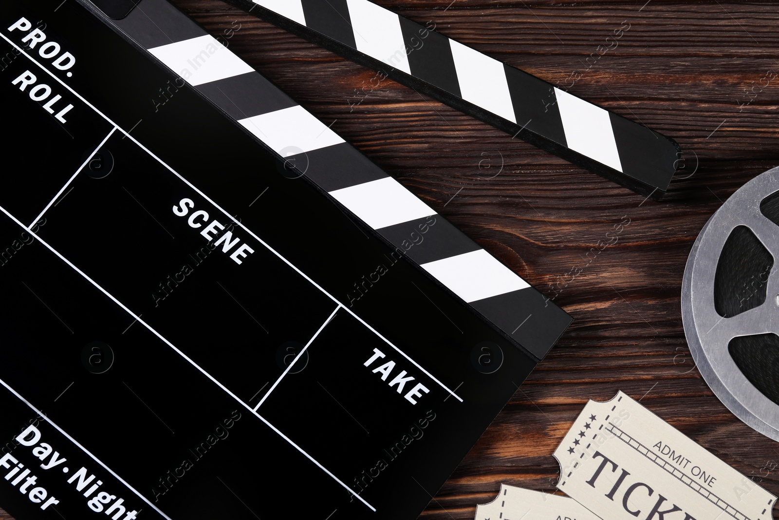 Photo of Clapperboard, movie tickets and film reel on wooden table, flat lay