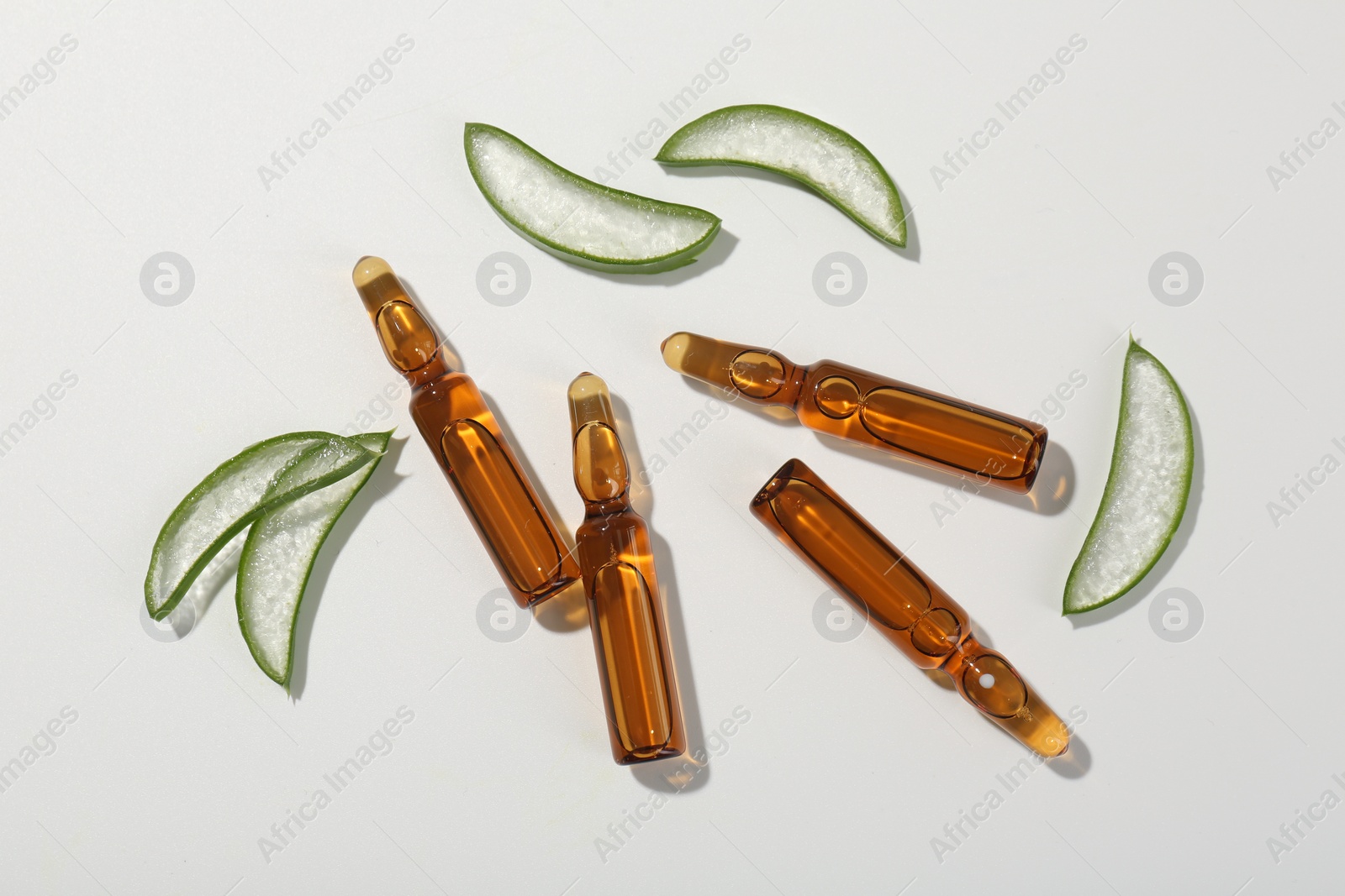 Photo of Skincare ampoules and cut aloe leaves on white background, flat lay