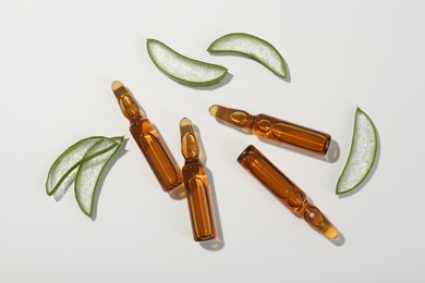 Skincare ampoules and cut aloe leaves on white background, flat lay