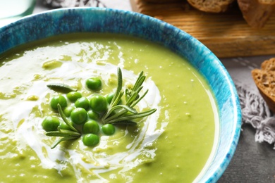 Photo of Fresh vegetable detox soup made of green peas in dish on table, closeup