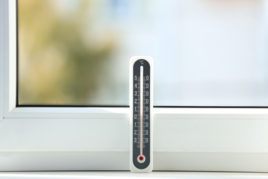 Grey weather thermometer on window sill indoors