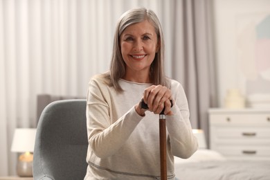Photo of Mature woman with walking cane on chair at home