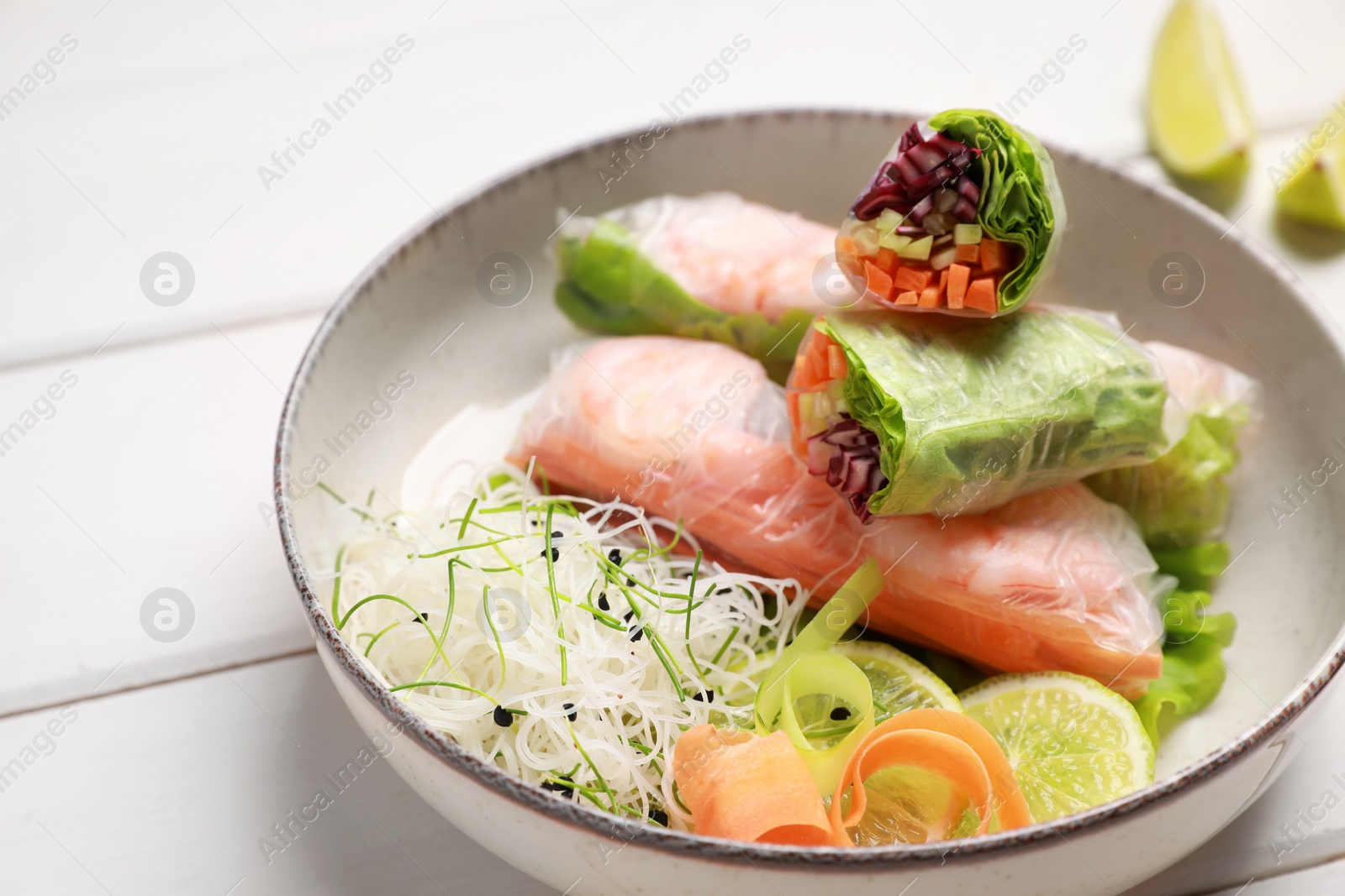 Photo of Delicious spring rolls wrapped in rice paper on white wooden table, closeup