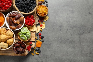 Photo of Bowls of different dried fruits on grey background, top view with space for text. Healthy food