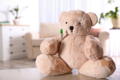 Photo of Stuffed teddy bear on table in child hospital. Space for text