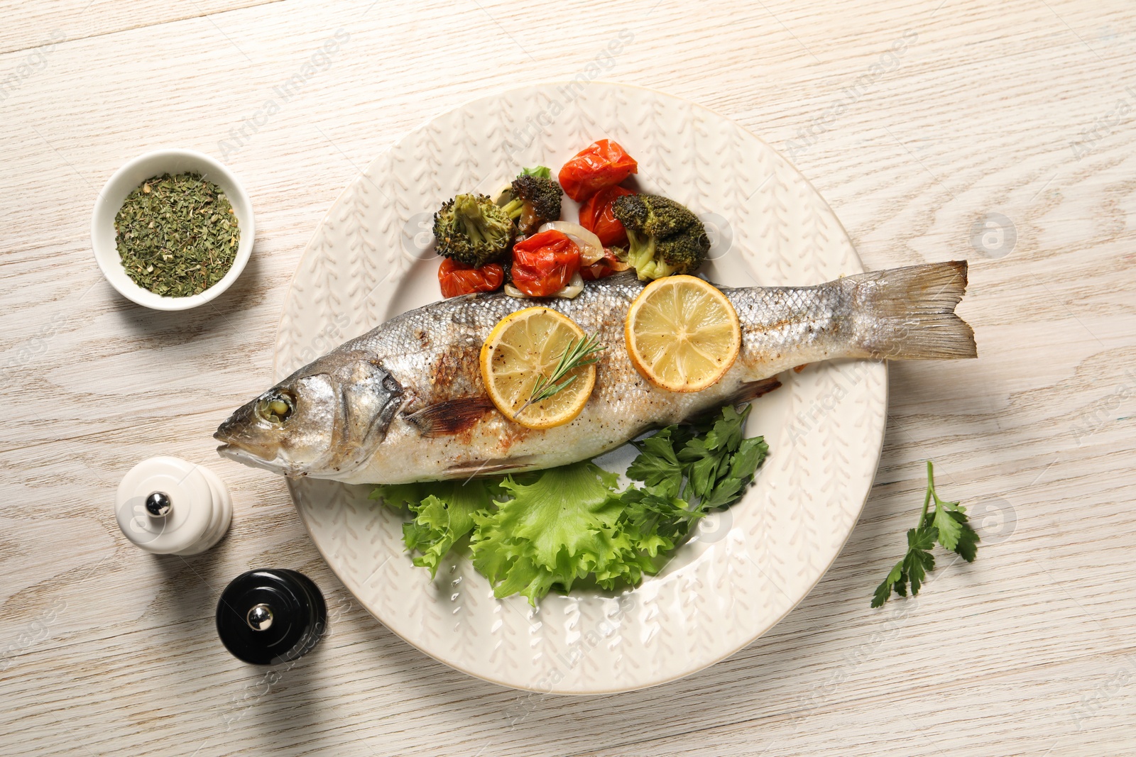 Photo of Delicious baked fish and vegetables served on wooden table, flat lay