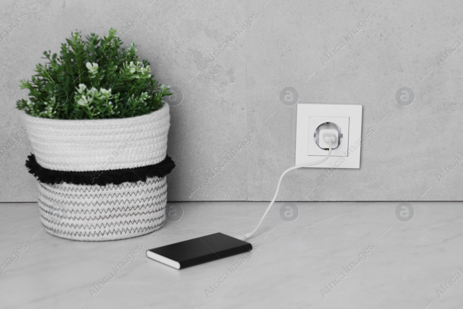 Photo of Power bank plugged into electric socket on white table