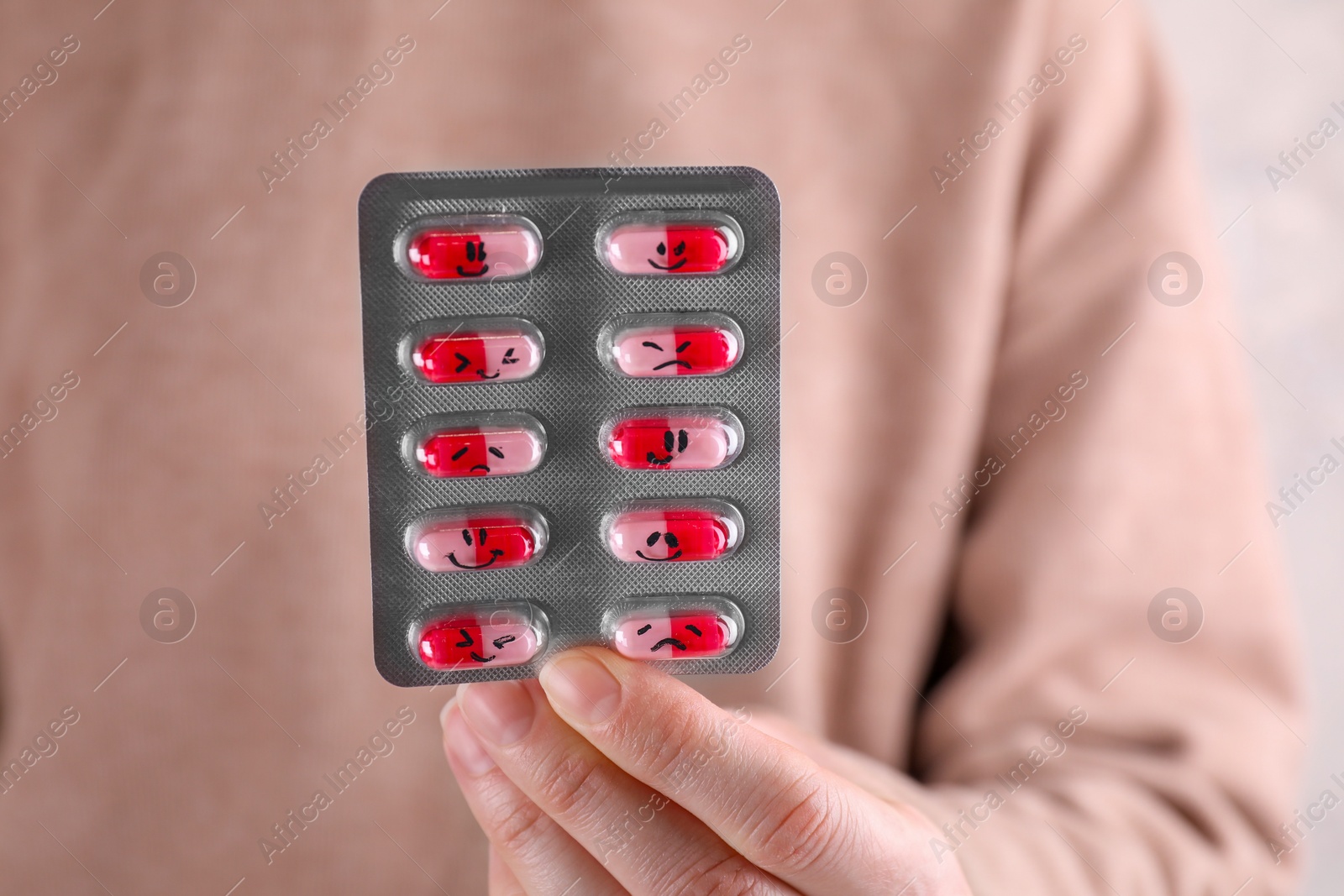 Photo of Woman holding blister of antidepressants with different emoticons, closeup view