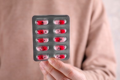 Photo of Woman holding blister of antidepressants with different emoticons, closeup view
