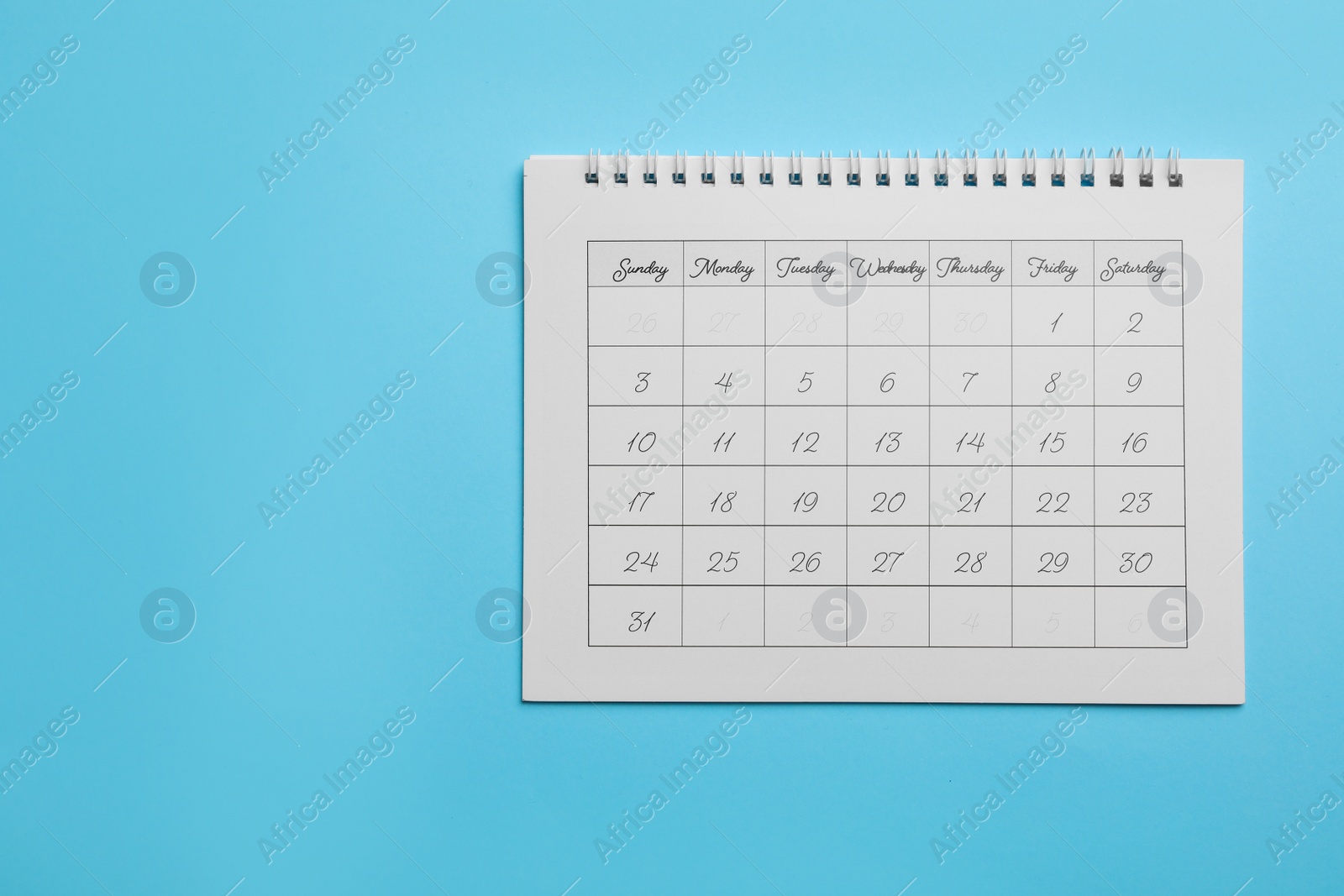 Photo of Paper calendar on light blue background, top view. Space for text