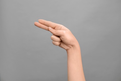 Photo of Woman showing H letter on grey background, closeup. Sign language