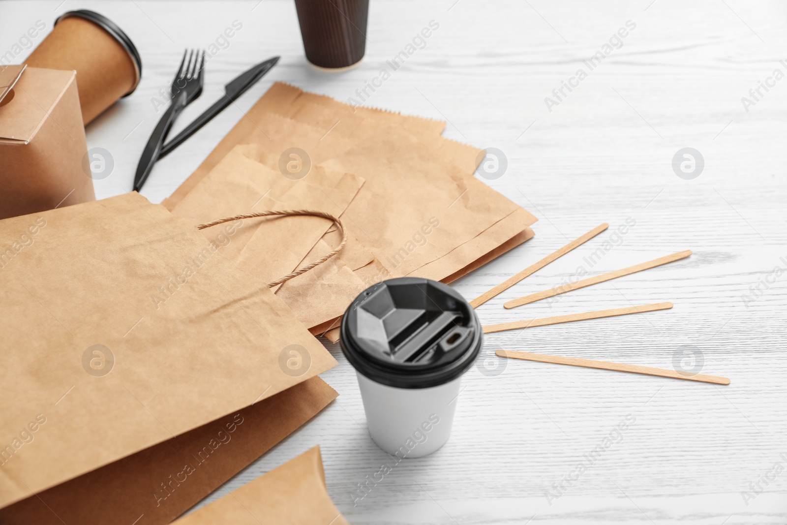 Photo of Paper bags and different takeaway items on wooden background. Space for design