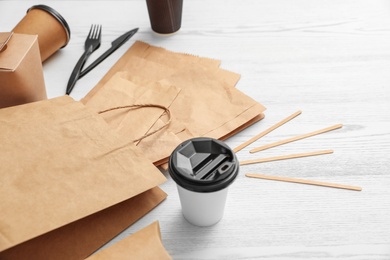 Photo of Paper bags and different takeaway items on wooden background. Space for design