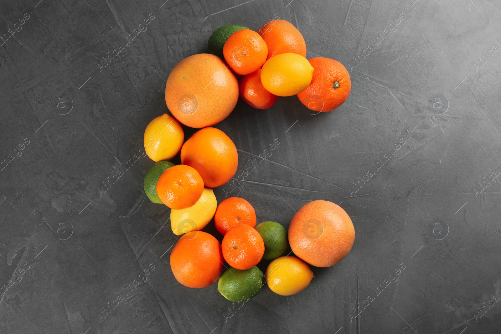 Photo of Letter C made with citrus fruits on grey table as vitamin representation, flat lay