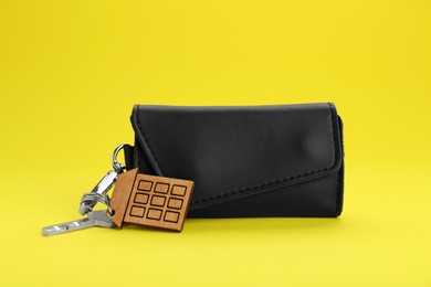 Photo of Leather case with key on yellow background