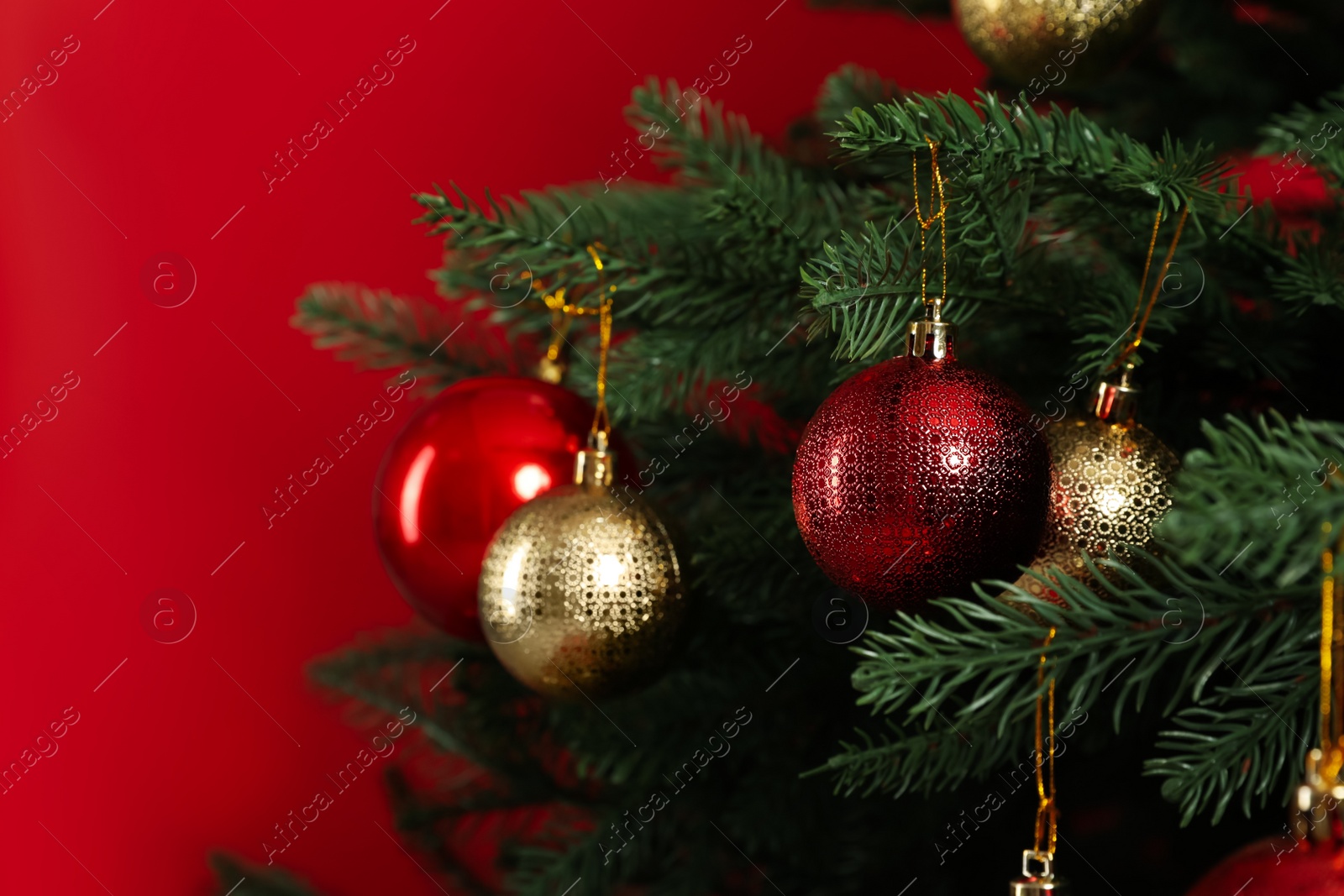 Photo of Beautifully decorated Christmas tree on red background, closeup